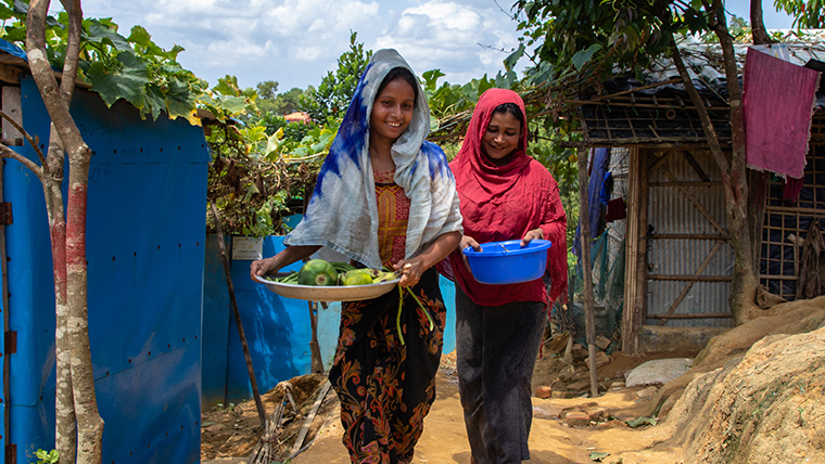 Rohingya women walk together through the refugee camp
