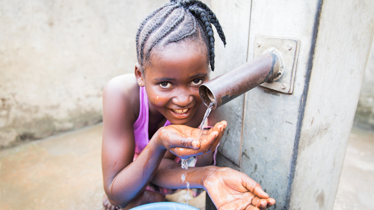 Isata drinks clean water from the fresh source near her home